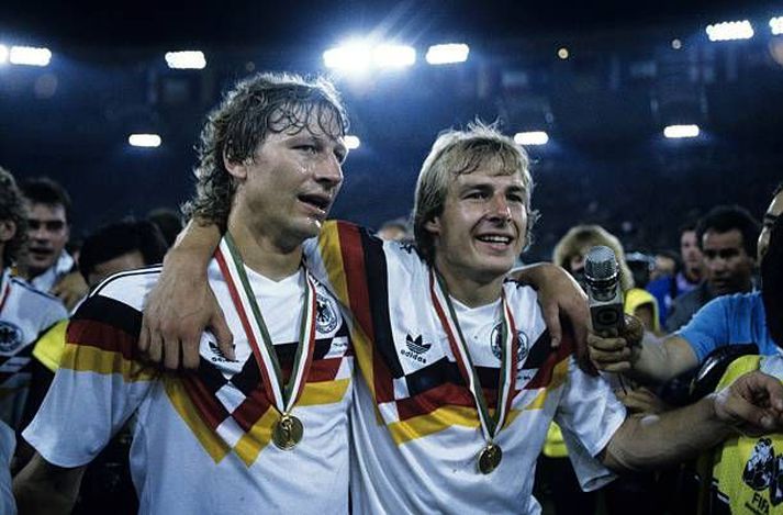 Guido Buchwald og Jurgen Klinsmann klæddir einhverjum íkonískustu treyjum allra tíma. Gullmedlalía HM 1990 um hálsinn. 