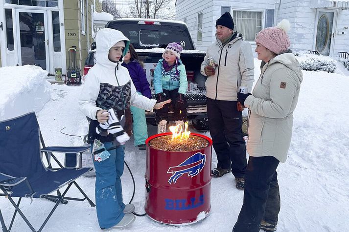 Nágrannar í Buffalo hlýja sér við opin eld eftir að hafa hjálpast að við að moka snjó.