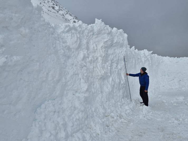 Gestur við sex metra skafl úr snjóflóðinu sem féll við Siglufjörð um helgina. 
