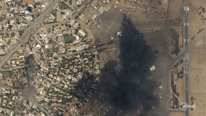 Á myndinni sést reykjamökkur stíga frá tveimur brennandi flugvélum á alþjóðaflugvellinum í Khartoum. 