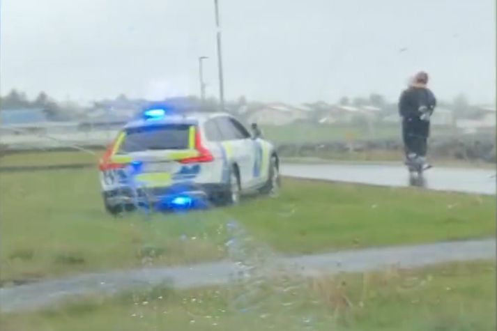 Lögreglubílinn á grasinu við göngustíginn og góðkunningjarnir á rás eftir stígnum.