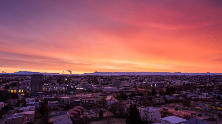 Himininn logaði gulur, bleikur og appelsínugulur í morgun. Myndin er tekin í Hlíðahverfi yfir Kringluna. Í fjarska sést gufa frá Hellisheiðarvirkjun og Bláfjöll.