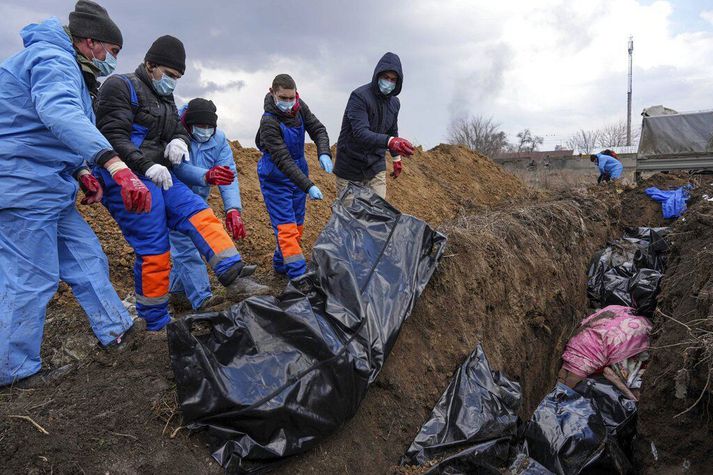 Lík látinna liggja á víð og dreif á götum úti í Mariupol. Þeim er komið fyrir í fjöldagröf þegar færi gefst á milli sprengjuárása.