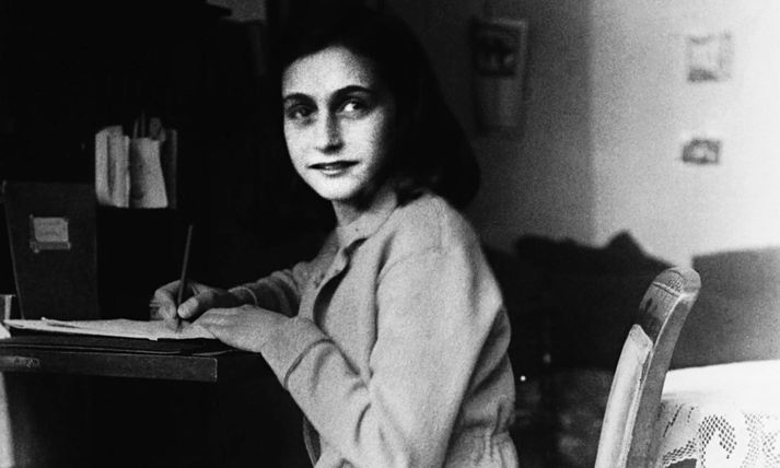 Anne Frank situr við skrifborðið þar sem hún byrjaði að skrifa í dagbækur sínar.