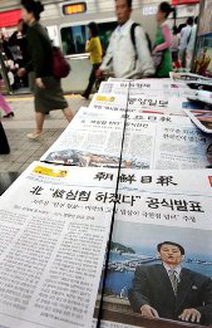 Farþegar í neðanjarðar lestarkerfi Seoul borgar ganga framhjá dagblaði, en á forsíðu þess er sagt frá sjónvarpstilkynningu Norðanmanna um kjarnorkutilraunir.