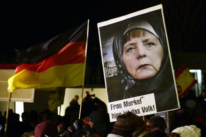 „Frú Merkel, hér er þjóðin,“ stendur á skilti við mynd af Angelu Merkel kanslara, sveipaðri slæðu og dapurri á svip.