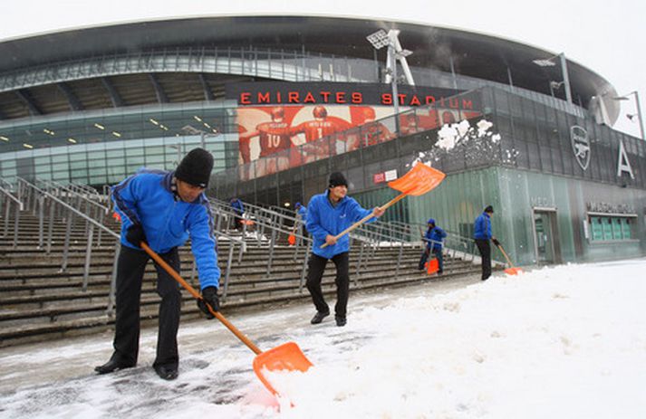 Starfsmenn Arsenal moka snjó fyrir utan Emirates-leikvanginn.