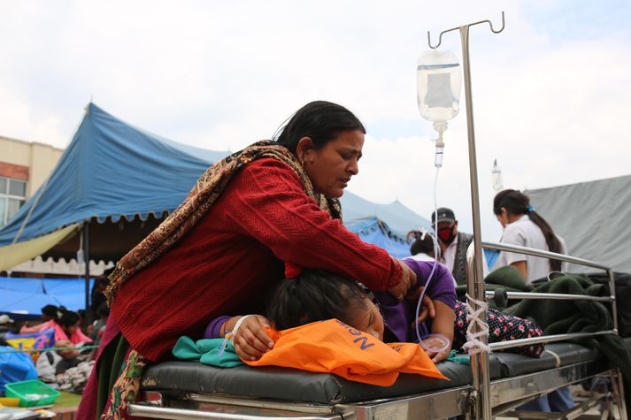 Móðir hlúir að slasaðri dóttur sinni fyrir utan Tribhuvan sjúkrahúsið í Nepal