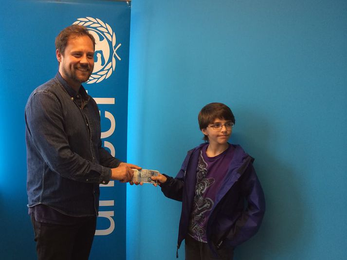 Howard Brown afhendir UNICEF þúsundkallana sjötíu.