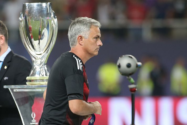 Jose Mourinho strunsar framhjá bikarnum í gær með verðlaunapeninginn í hendinni.