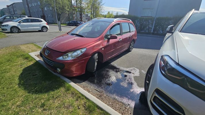 Bíllinn er á bílastæði í Stigahlíð og yfirfullur af bensínbrúsum.