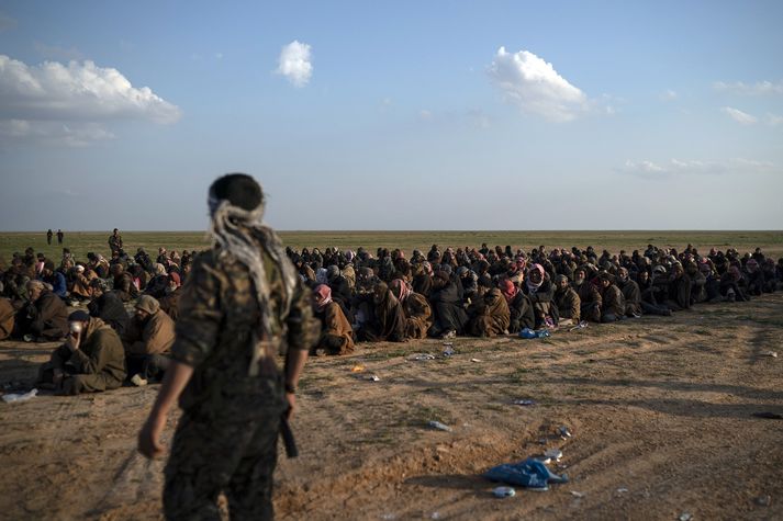 SDF-liði stendur vörð um menn frá Baghouz.