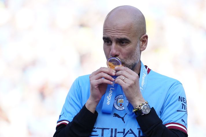 Pep Guardiola kyssir verðlaunapeninginn sem hann fékk eftir sigur Manchester City í ensku úrvalsdeildinni.