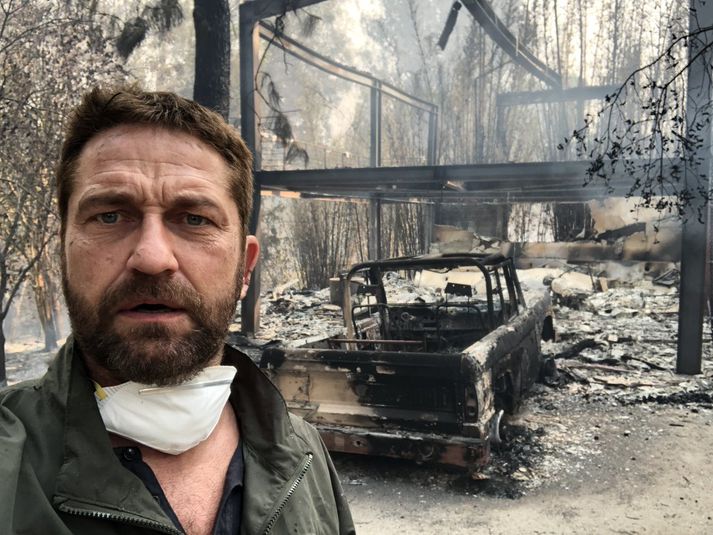 Gerard Butler fyrir framan brunarústirnar.