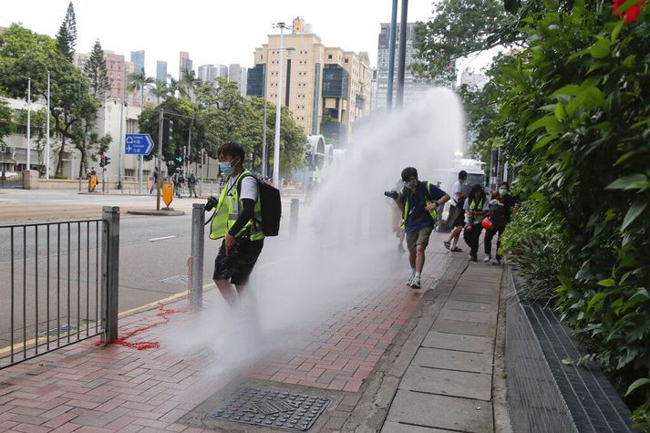 Lögreglan í Hong Kong sést hér beita vatni gegn blaðamönnum sem fylgdist með aðgerðum hennar í borginni í gær.