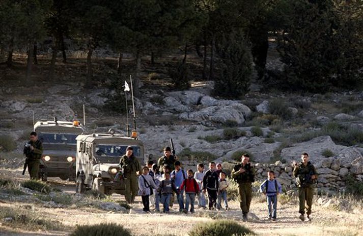 Ísraelskir hermenn fyglgja palestínskum börnum í skólann við Havat Maon í útjaðri Vesturbakkans.