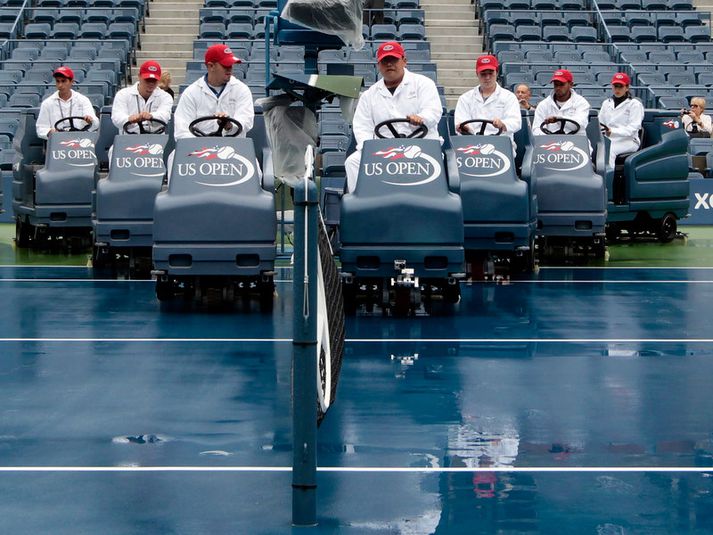 Starfsmenn reyna hér að þurka einn völlinn sem keppt er á opna bandaríska meistaramótinu í tennis.