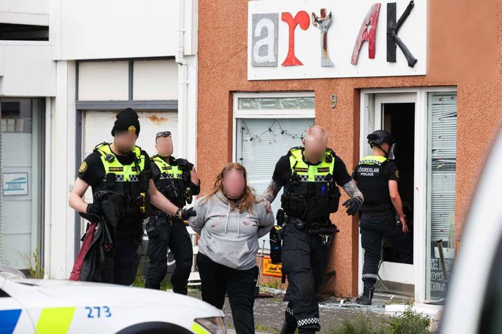 Kona var leidd í járnum út úr húsnæðinu. Rauðir blettir voru á peysunni hennar.