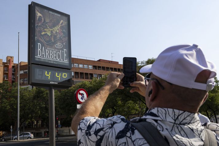 Ferðamaður í Sevilla myndar skilti sem sýnir 44 stiga hita. 