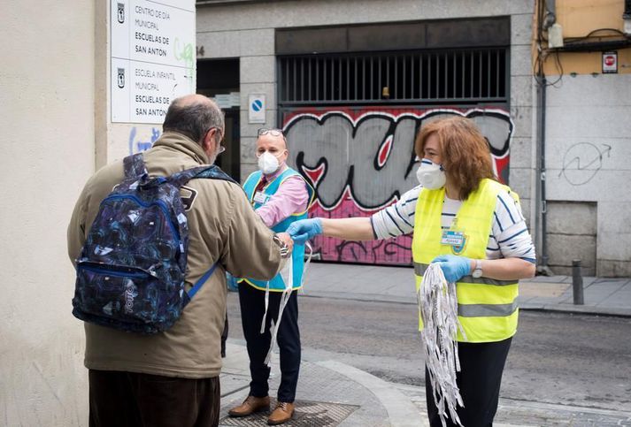 Sjálfboðaliðar dreifa andlitsgrímum og matvælum til bágstaddra í San Antón-kirkjunni í Madrid. Hlutfall smitaðra í borginni er eitt það hæsta á Spáni.