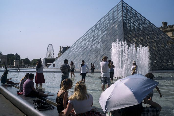 Parísarbúar reyna að kæla sig í gosbrunni við Louvre-safnið.