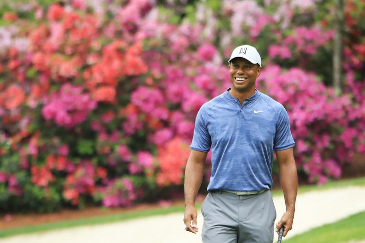Tiger Woods brosandi á æfingahring á Augusta National golfvellinum.
