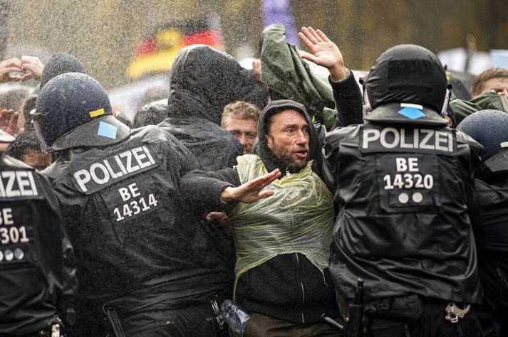 Þýskir lögreglumenn ýtta mótmælendum til baka við Brandenborgarhliðið í Berlín í dag. Kallaður var til liðsauki lögreglumanna frá öðrum landshlutum til að takast á við mótmælin gegn sóttvarnaaðgerðum.