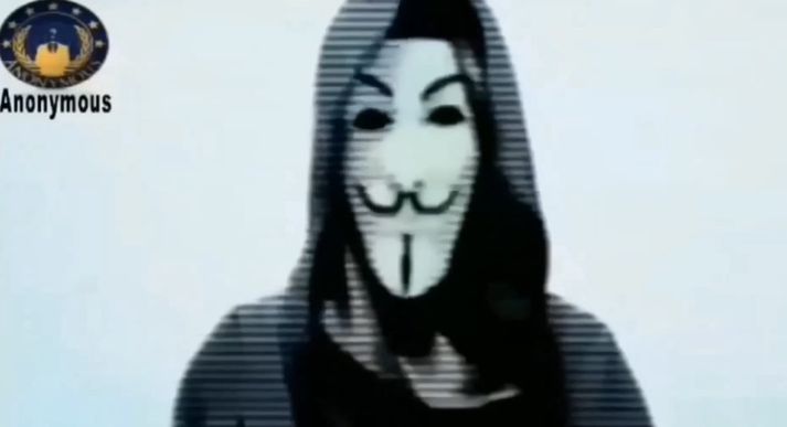 Maður með Guy Fawkes grímu les skilaboð Anonymous til hryðjuverkamanna.