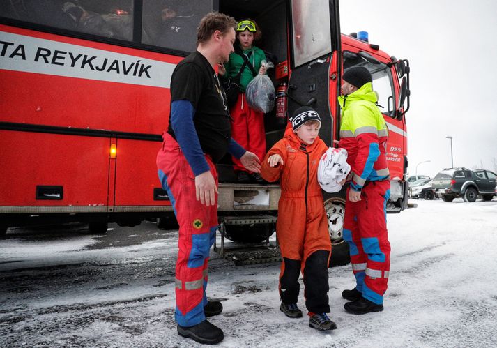 Björgunarsveitarmenn aðstoða börn út úr bílnum við Malarhöfða við komuna til Reykjavíkur á mánudag.