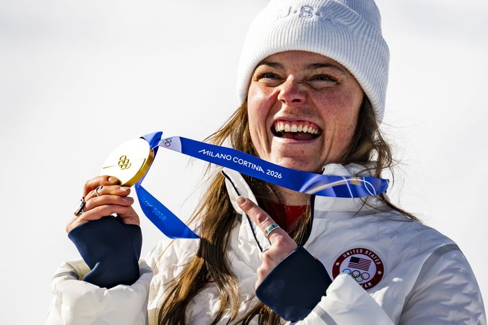 Breezy Johnson fagnar með Ólympíugullið sem hún vann í bruni. Hún komst ekki á pall í risasviginu en fékk engu að síður verðlaun í markinu, bara af allt öðrum toga.