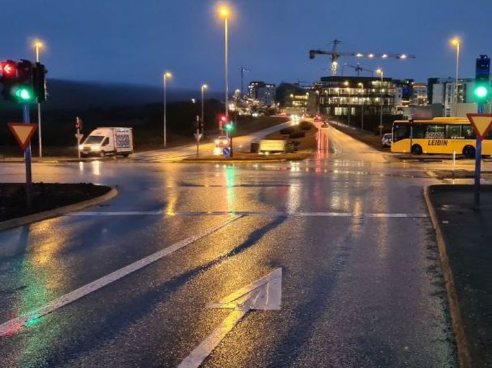 Mynd tekin í akstursátt bifreiðarinnar. Rautt ljós logar fyrir vinstri beygju og grænt fyrir akreinina yfir gatnamótin.