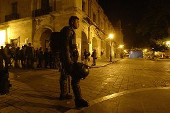 Mexíkóskur alríkislögreglumaður fylgist með þróun mála í miðbæ Oaxaca í Mexíkó.