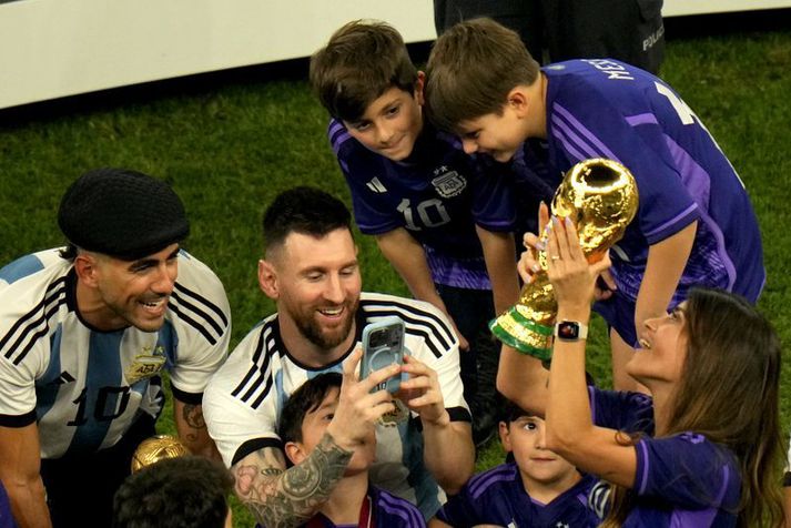 Lionel Messi myndar eiginkonu sína Antonela Roccuzzo með heimsbikarinn umkringdur sonum sínum þremur.