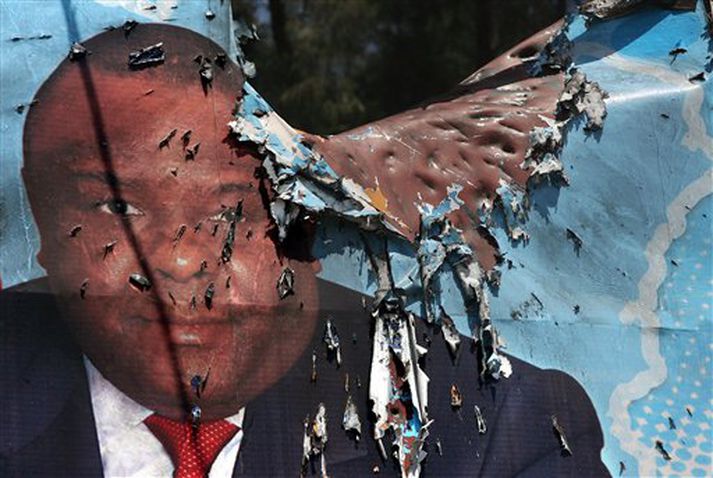 Jean-Pierre Bemba biðlar til kjósenda af auglýsingaskilti sem hefur orðið fyrir sprengjuárás. Myndin lýsir vel ástandinu í Austur-Kongó þar sem ítrekað hefur komið til átaka milli stjórnarhermanna sem hliðhollir eru Kabila, sitjandi forseta, og hins vegar vígamanna sem ganga erinda uppreisnarleiðtogans Bemba.