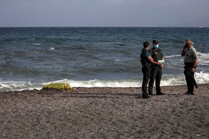 Lögregluþjónar standa nærri líki manns sem rak á land í Ceuta. Maðurinn hafði reynt að synda frá Marokkó til yfirráðasvæðis Spánar.