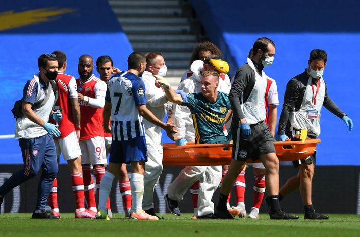 Bernd Leno borinn af velli og bendir á Neal Maupay sem braut á honum.