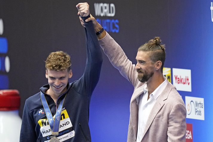 Michael Phelps með Leon Marchand eftir að hafa afhent honum HM-gullið.
