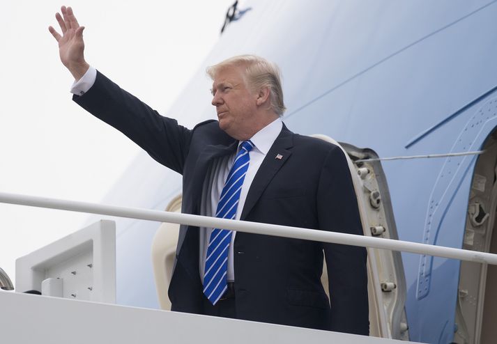 Donald Trump veifar áður en hann leggur af stað til Evrópu.