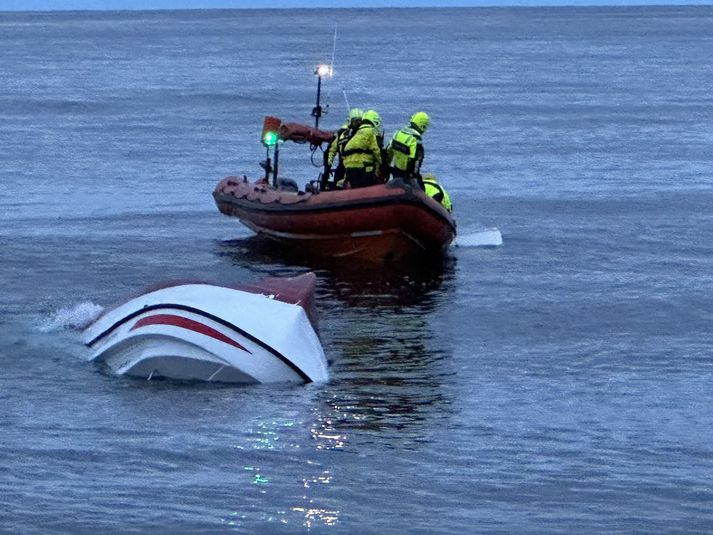 Björgunarmenn á vettvangi, þar sem báturinn marar í hálfu kafi.