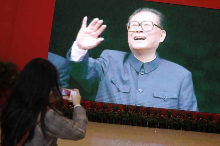 Kona tekur mynd af mynd af Jiang Zemin, fyrrverandi forseta Kína, á þjóðmiðjasafni í Beijing árið 2018.