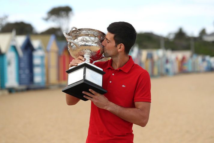 Novak Djokovic smellir kossi á verðlaunagripinn á ströndinni í Melbourne fyrir tæpu ári síðan.