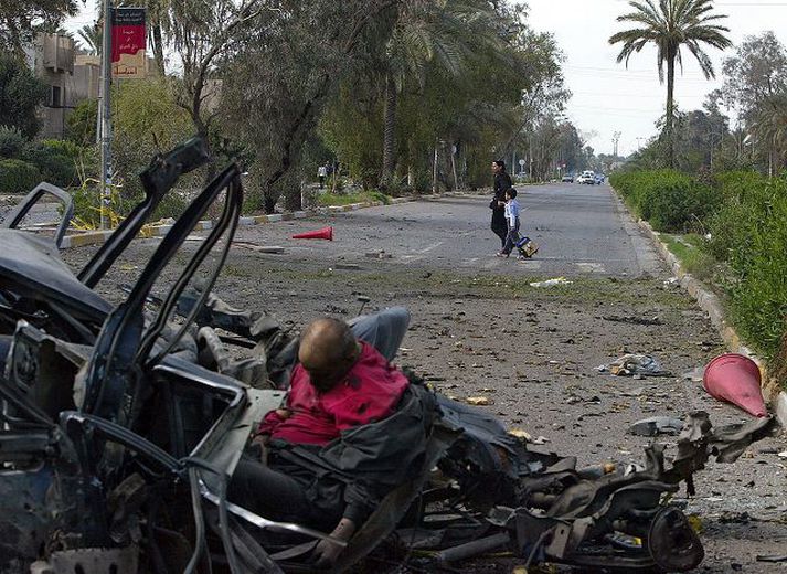 Írösk mæðgin ganga framhjá bíl með líki sjálfsmorðsárásarmanns.