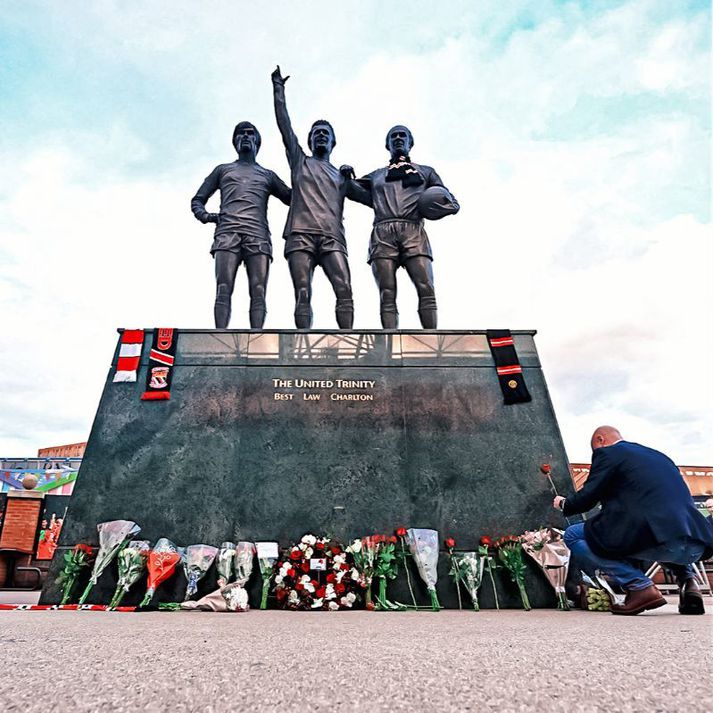 Mynd af United Trinity styttunni fyrir utan Old Trafford í morgun. Sir Bobby Charlton hægra megin með trefil sér um háls, Denis Law er fyrir miðju og George Best vinstra megin. 