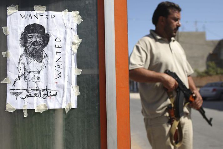 Á veggspjaldi er lýst eftir Múammar Gaddafí.
nordicphotos/AFP