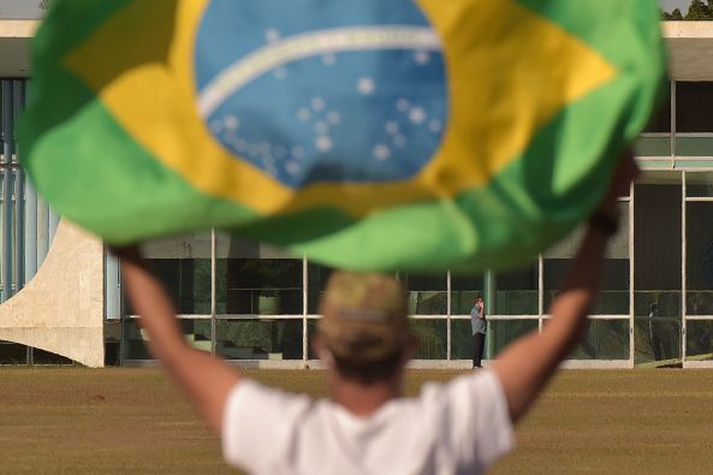 Bolsonaro, sem hér sést í bakgrunninum eftir að hann smitaðist af kórónuveirunni, hefur verið gagnrýndur fyrir viðbrögð við faraldrinum.