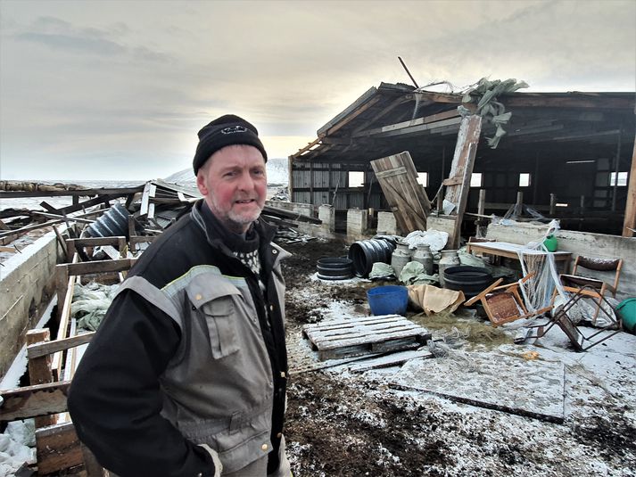 Magnús á Minna Hofi við hlöðuna og fjárhúsið á bænum, sem stórskemmdist í óveðrinu í gær.