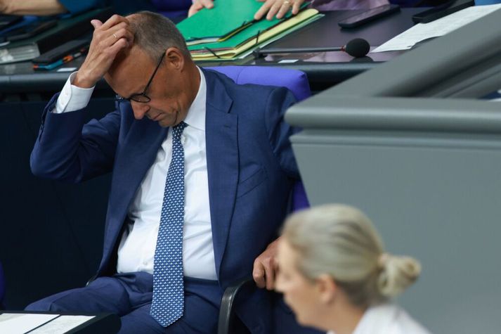 Friedrich Merz, kanslari, klórar sér í kollinum undir ræðu Alice Weidel, leiðtoga AfD, í þýska þinginu í dag. Weidel sagði Merz ekki hafa skilið skilaboðin sem kjósendur í Saxlandi-Anholt sendu honum um helgina.