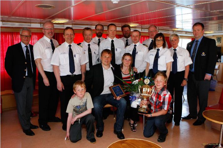 Óskar Matthíasson, skiptstjóri Bylgju VE 75, ásamt fjölskyldu sinni í fremri röð. Guðmundur Örn Jóhannsson framkvæmdastjóri SL og Hörður Már Harðarson formaður SL auk áhafnar Sæbjargar, skólaskips Slysavarnaskóla sjómanna í aftari röð.