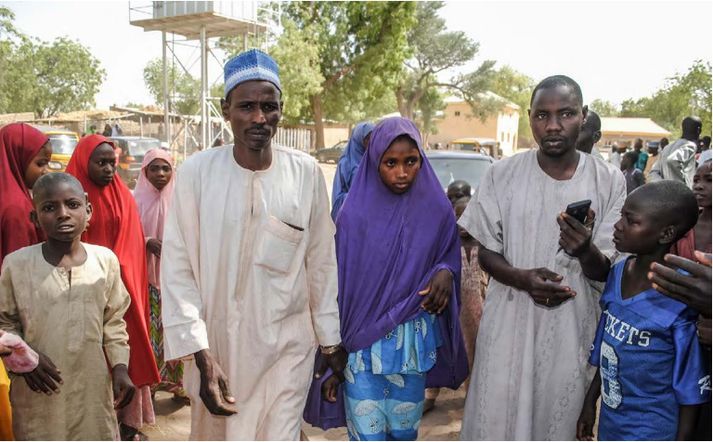 Stúlka, sem hryðjuverkasamtökin Boko Haram slepptu á miðvikudag, gengur um götur heimabæjarins Dapchi með föður sínum.