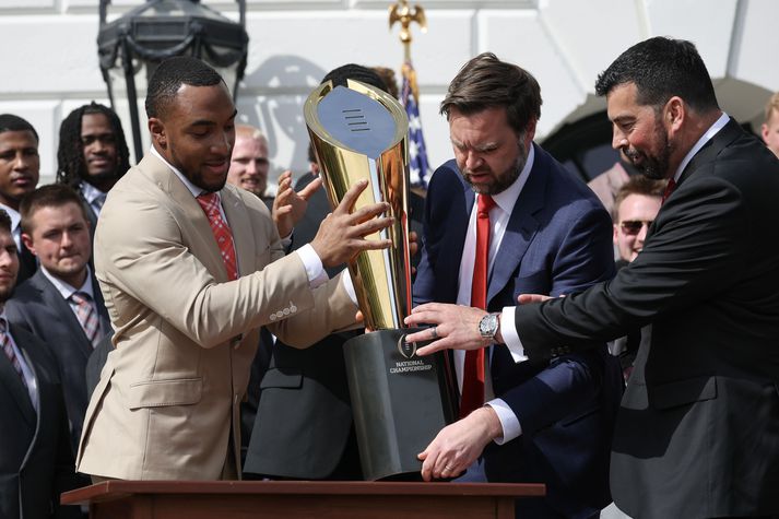 JD Vance, varaforseti Bandaríkjanna, sést hér reyna að setja bikarinn aftur saman ásamt þjálfara Ohio State háskólaliðsins, Ryan Day.